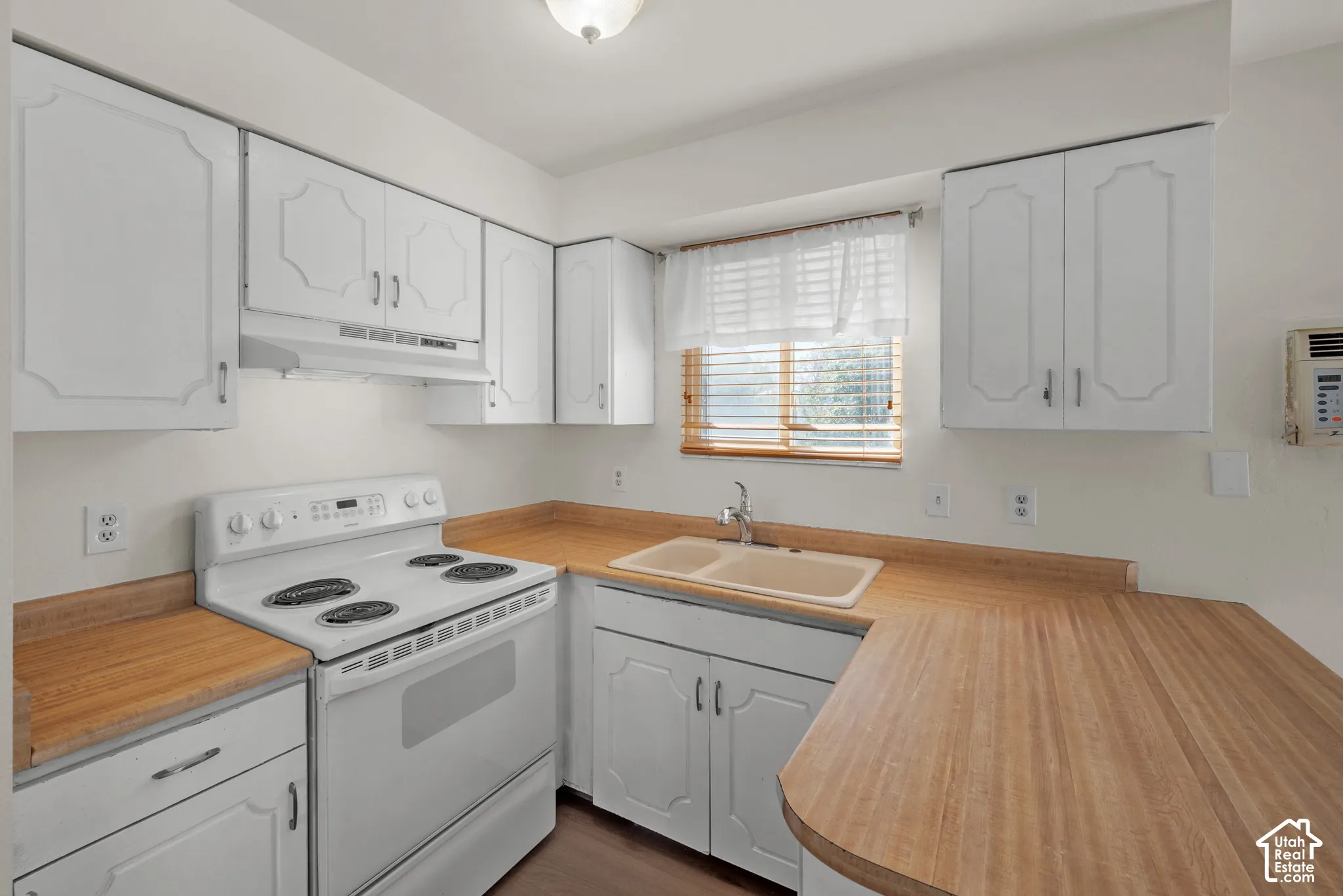 Kitchen featuring white cabinetry, wood-finish countertops, a double basin sink, and a white electric range