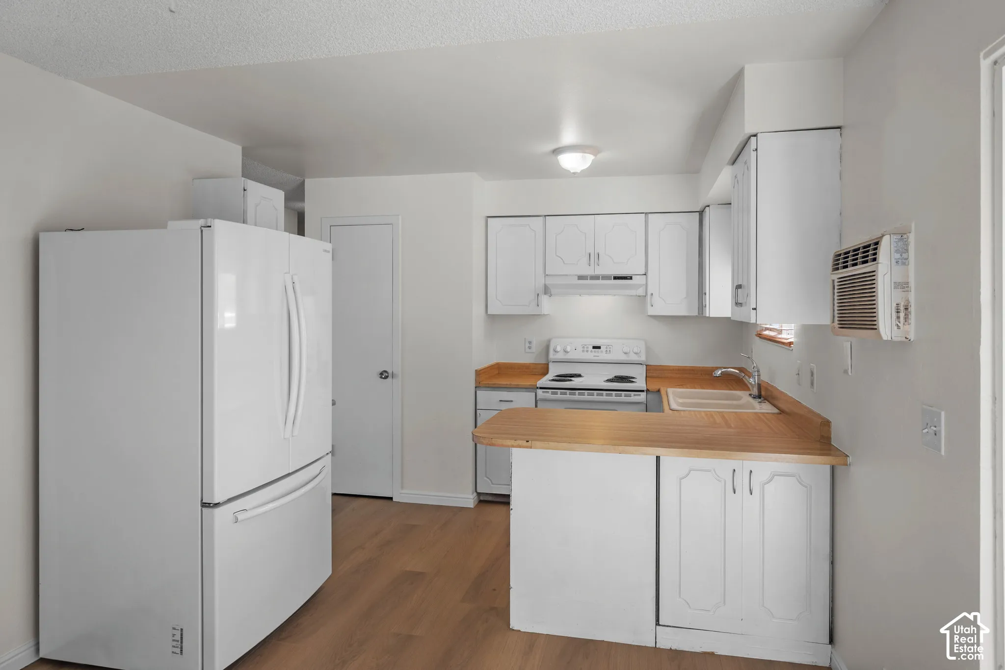 Kitchen featuring wood-finish flooring, white cabinetry, a white electric range, and a white refrigerator