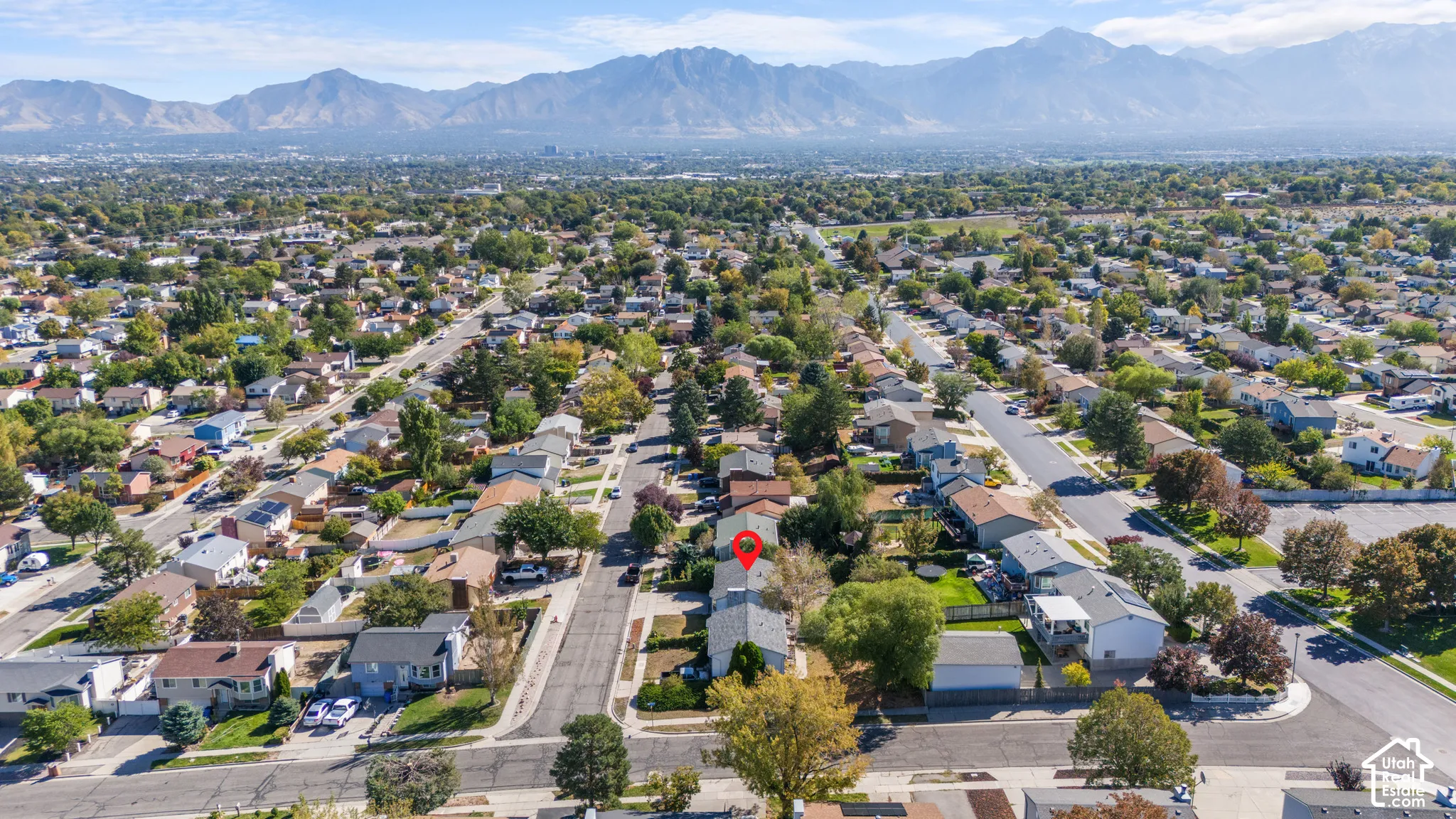 Aerial perspective of a residential neighborhood with tree-lined streets and mountain backdrop