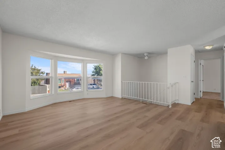 Spacious interior featuring wood-finish flooring, white walls, multiple windows, and a white railing