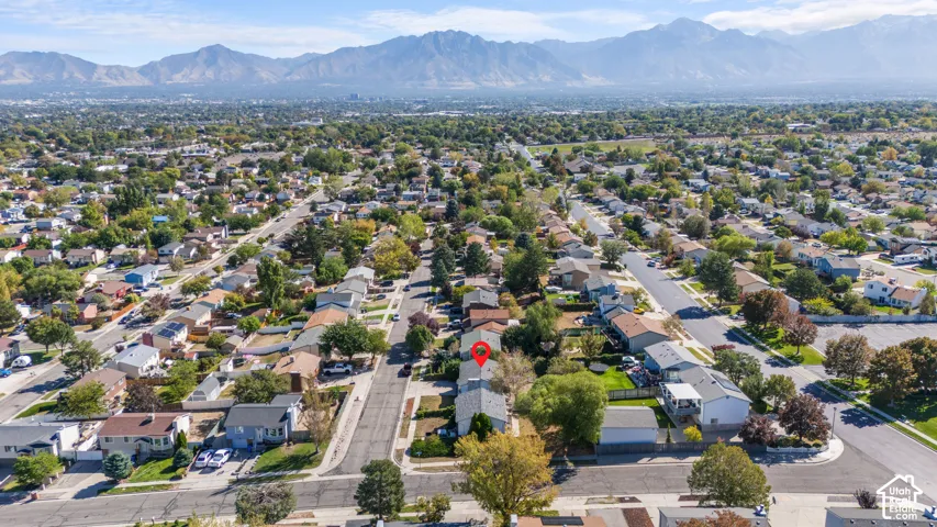 Aerial perspective of a residential neighborhood with tree-lined streets and mountain backdrop