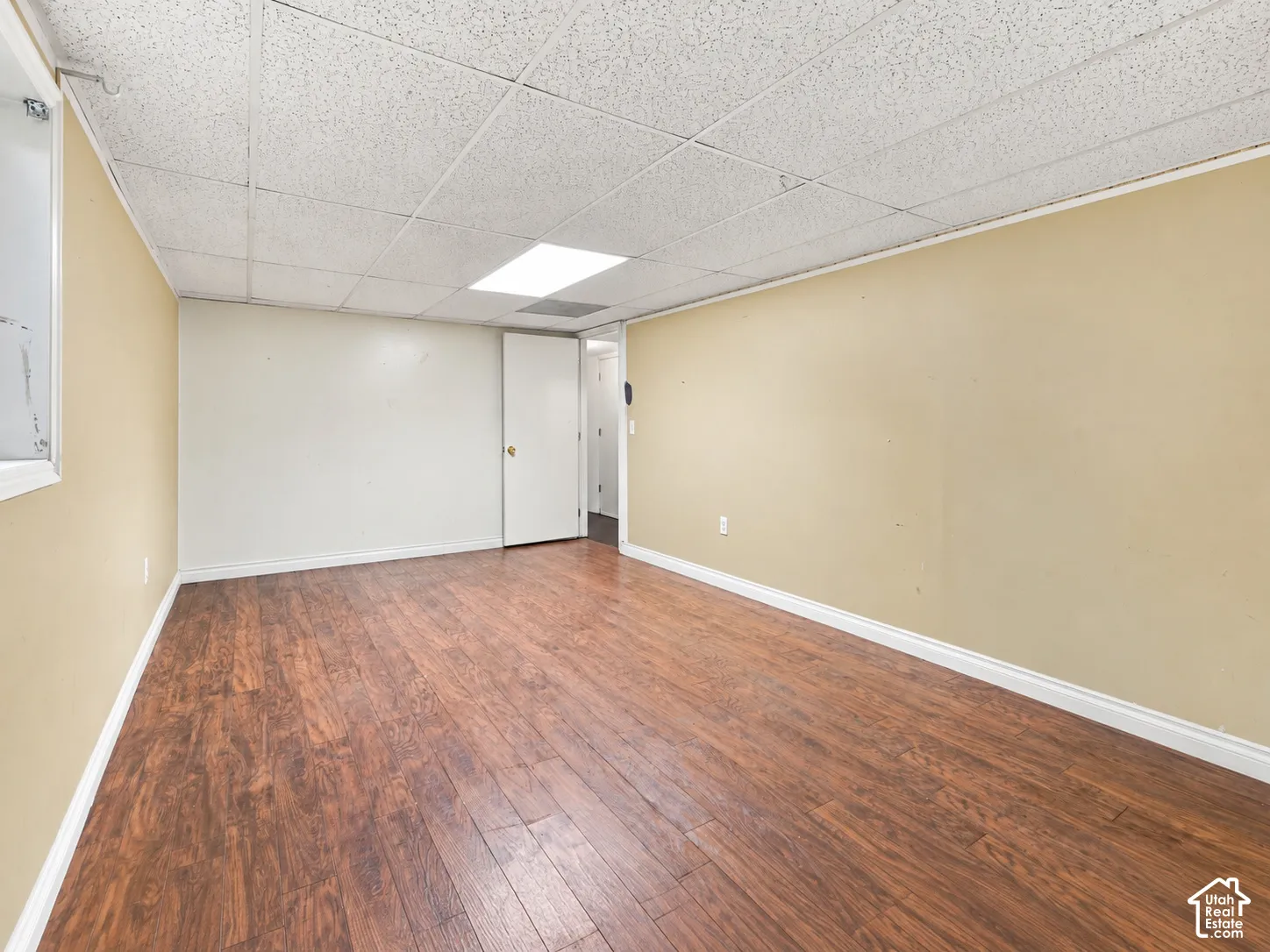 Wood-finish flooring with light beige walls and a white acoustical tile ceiling