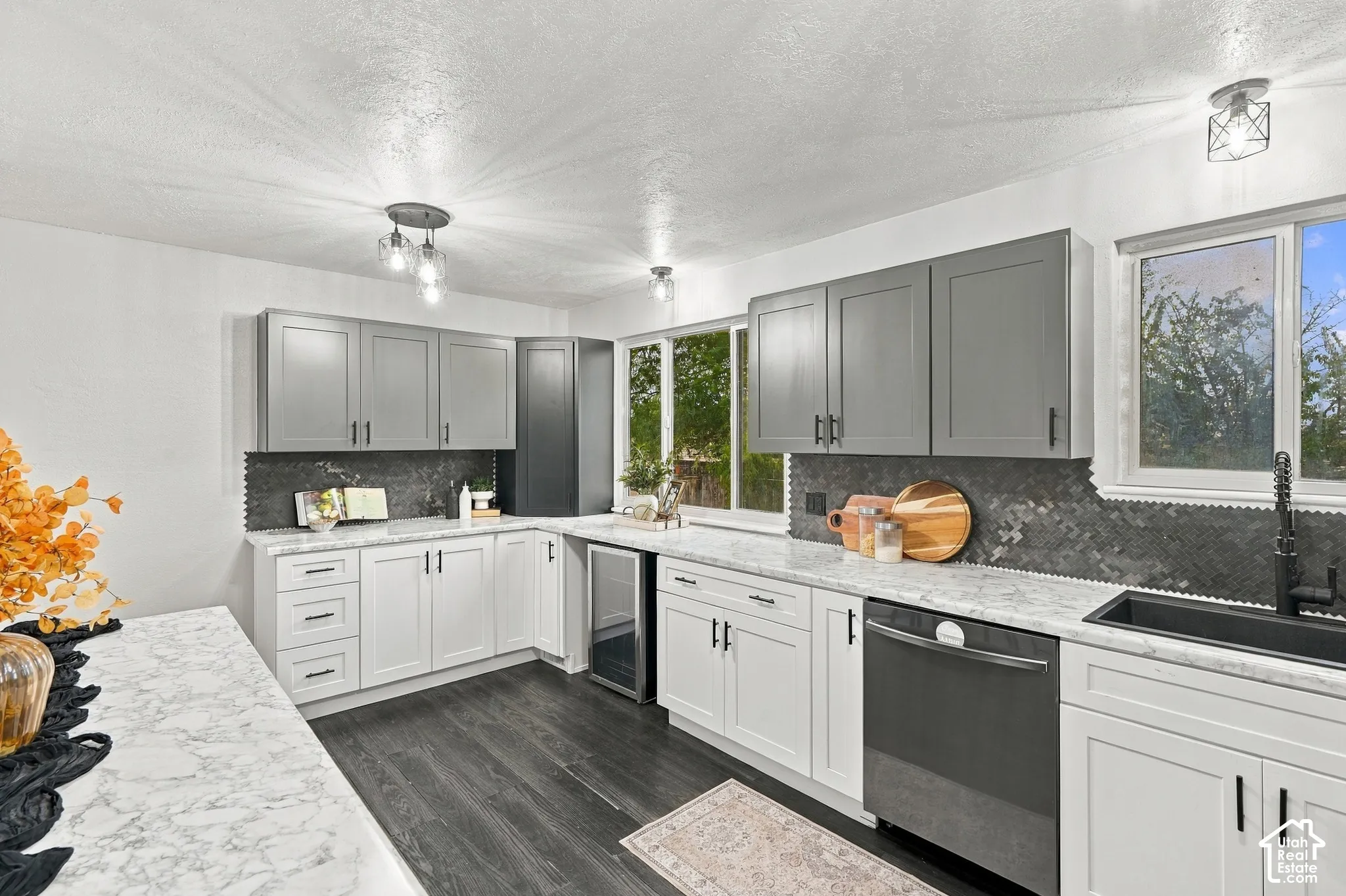 Kitchen featuring soft-close updated two-tone cabinetry, high-end stainless steel appliances, dark tile backsplash, and light countertops.