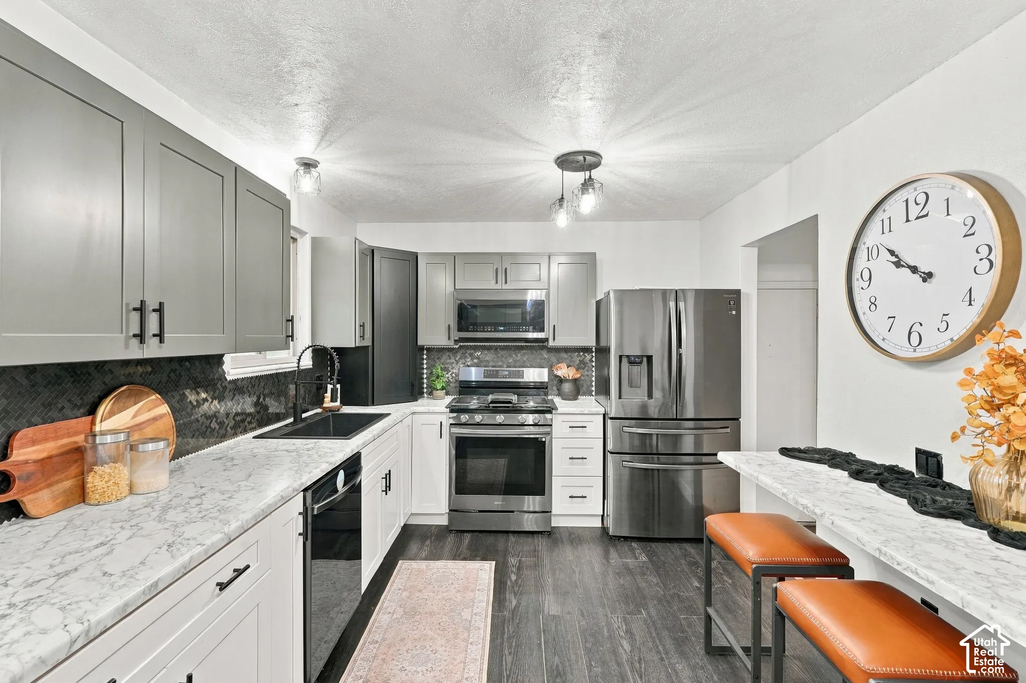 Kitchen featuring soft-close updated two-tone cabinetry, high-end stainless steel appliances, dark tile backsplash, and light countertops.