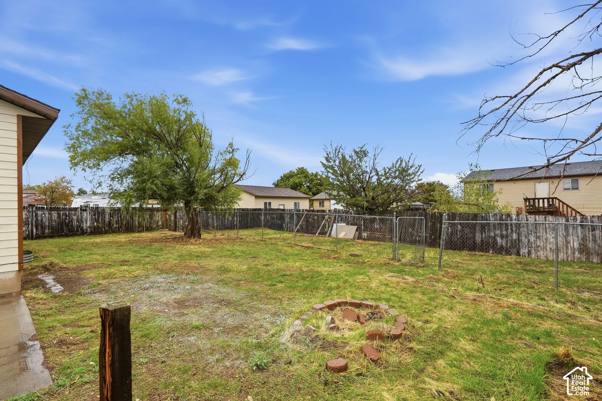 Expansive backyard featuring a mature tree, wood fencing, and full fence