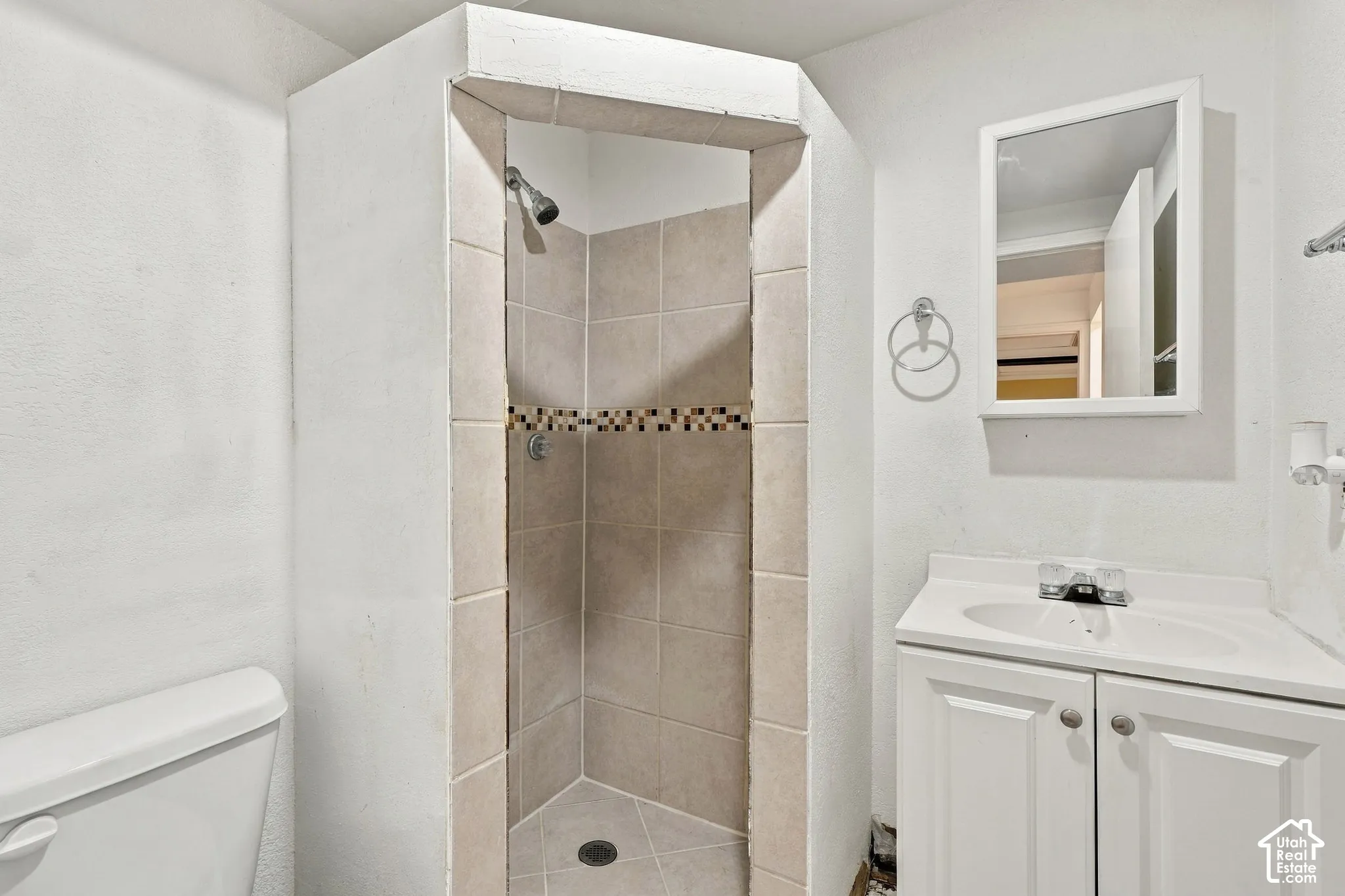 Angled shower stall with tile surround and decorative mosaic accent band