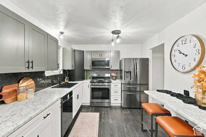 Kitchen featuring soft-close updated two-tone cabinetry, high-end stainless steel appliances, dark tile backsplash, and light countertops.