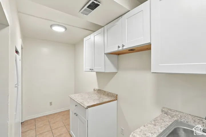 Basement 2nd Kitchen featuring white shaker-style cabinetry, light-colored countertops, tile flooring, stainless steel sink, and included fridge.