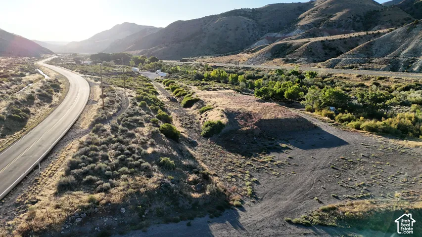 Mountainous backdrop with a paved road, natural terrain, and distant structures