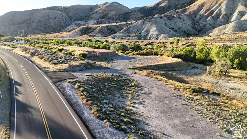Paved road with double yellow lines traversing a mountainous landscape, featuring natural desert vegetation and distant hills