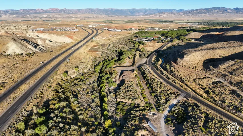 Expansive land featuring desert vegetation, paved roadways, and distant mountain ranges