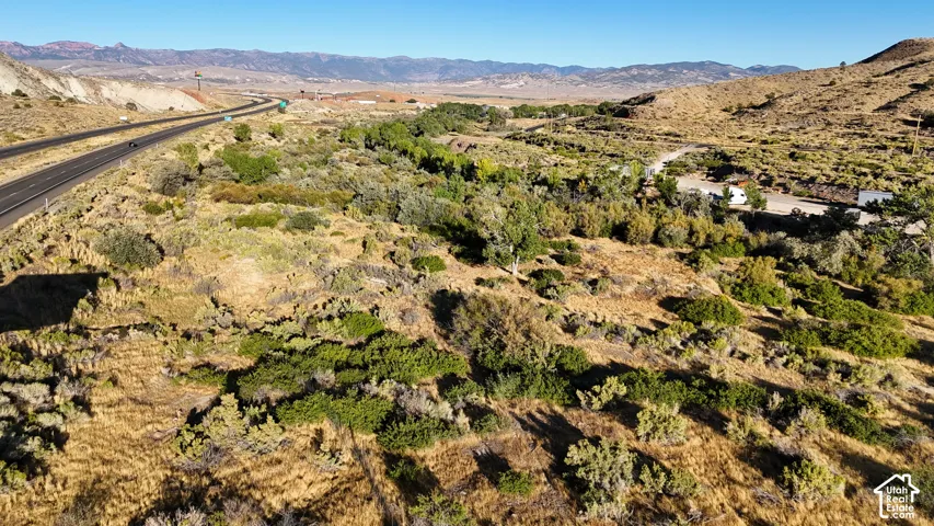 Expansive natural landscape featuring varied terrain, a winding road, and distant mountain ranges