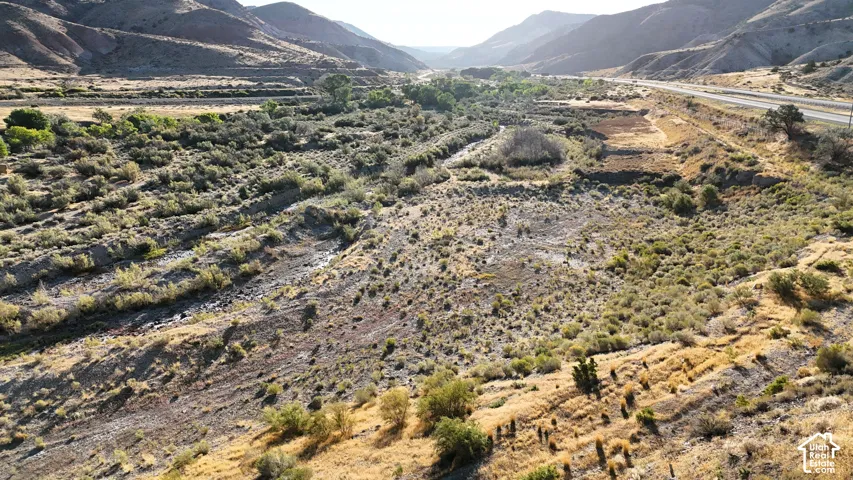Expansive natural landscape featuring varied terrain, a distant highway, and surrounding mountainous topography
