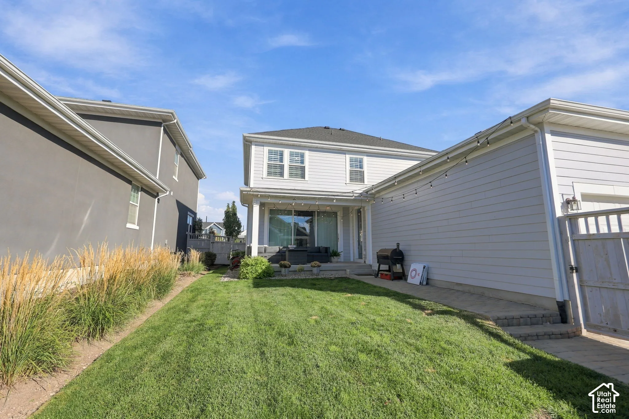 Expansive backyard featuring a manicured lawn, tiered paver patio, and low-maintenance landscaping
