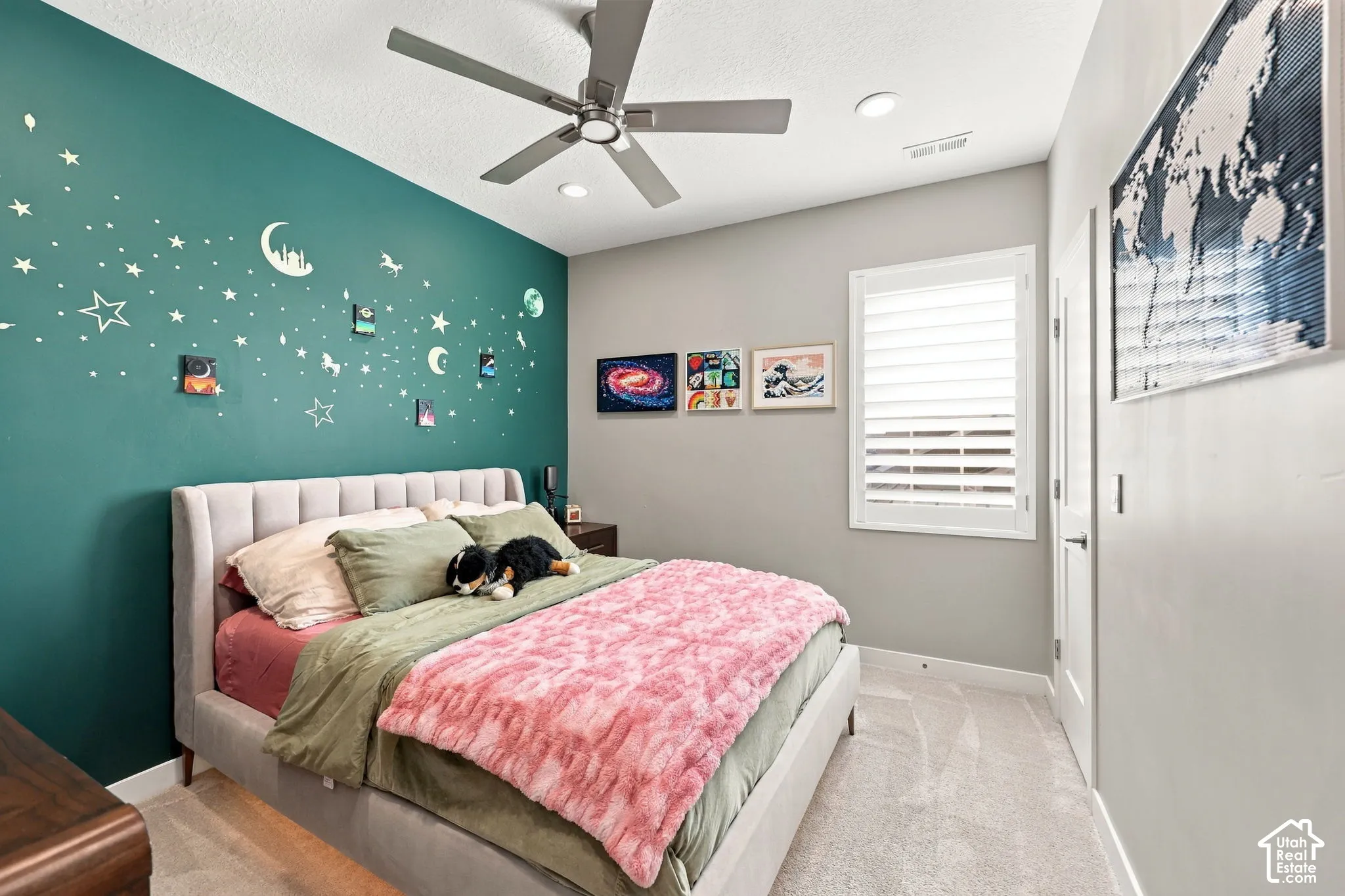 Recessed lighting, ceiling fan, window with plantation shutters, plush carpeting, and a contrasting accent wall