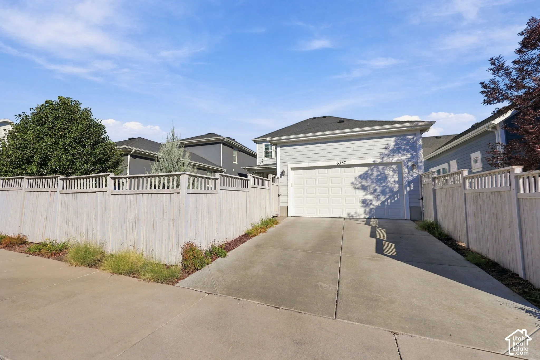 Attached garage with panel door, concrete driveway, and light-colored horizontal siding
