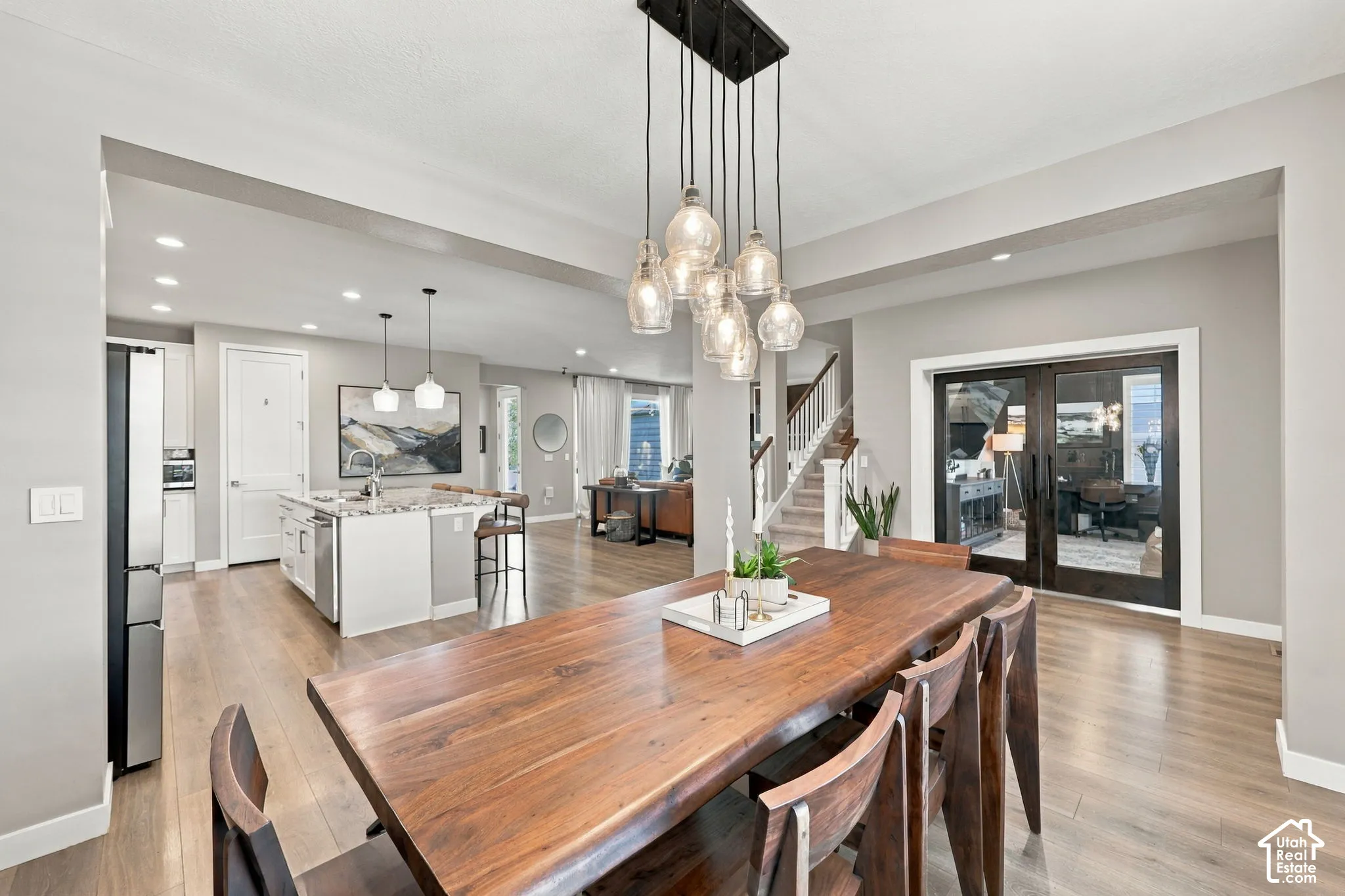 Dining area with a multi-light pendant fixture, wood-finish flooring, and a kitchen island with pendant lighting