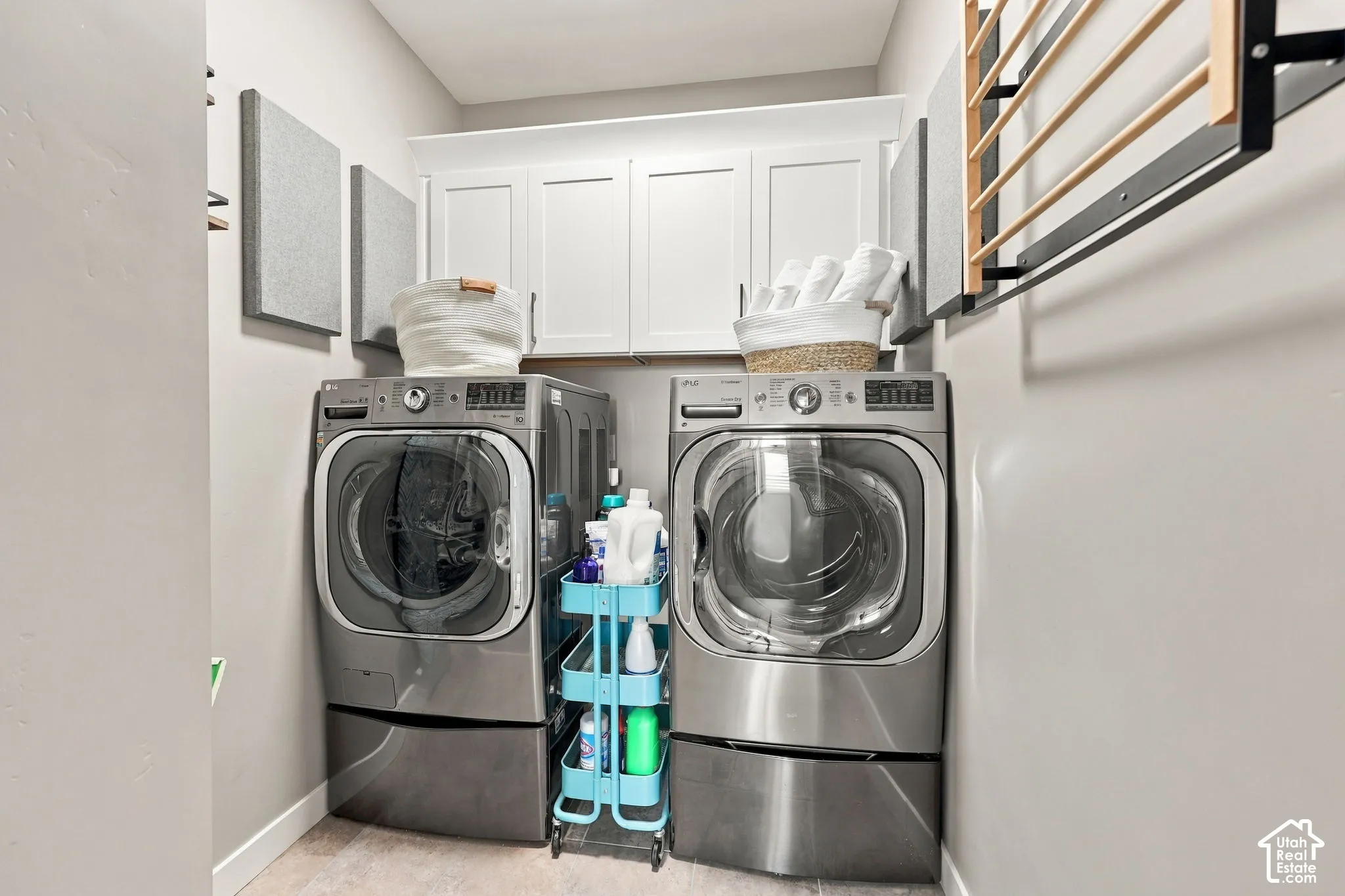 Laundry area featuring light wood-finish flooring, white shaker-style cabinetry, and a wall-mounted drying rack