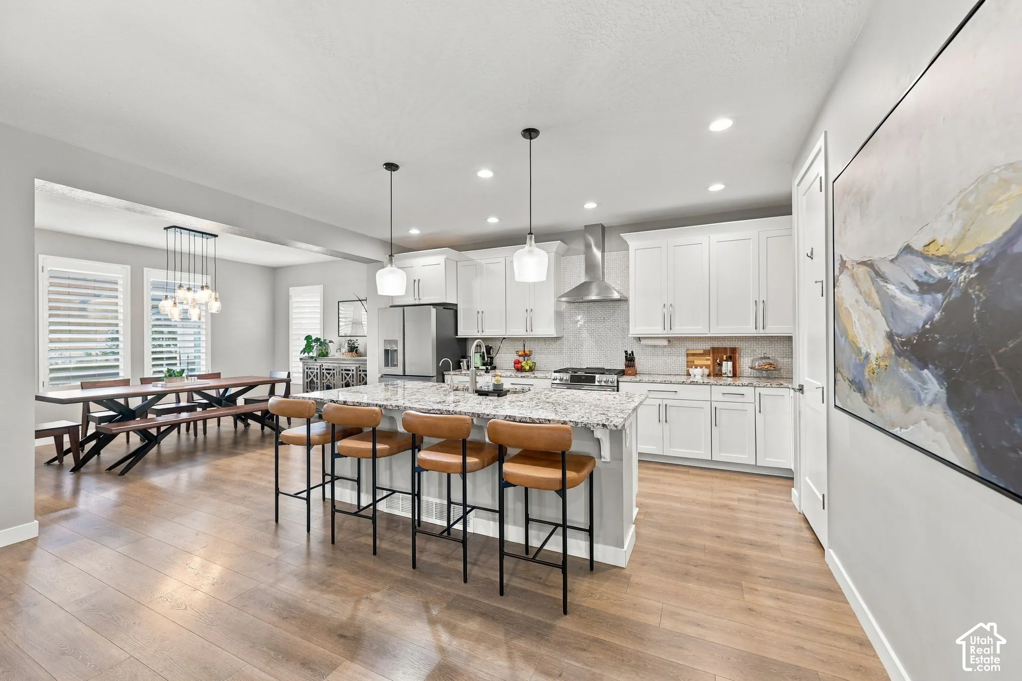 Open-concept kitchen and dining area featuring light wood-finish flooring, white cabinetry, a large kitchen island with counter seating, and recessed lighting