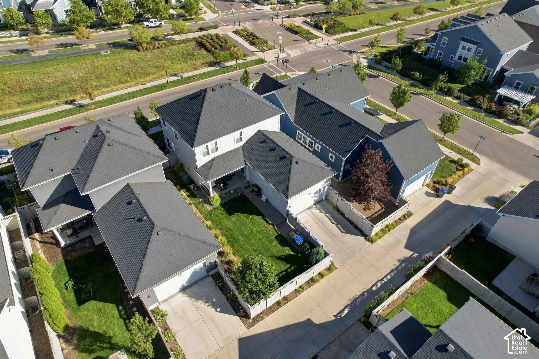 Multiple residential structures with dark shingle roofs, light-colored siding, and attached garages