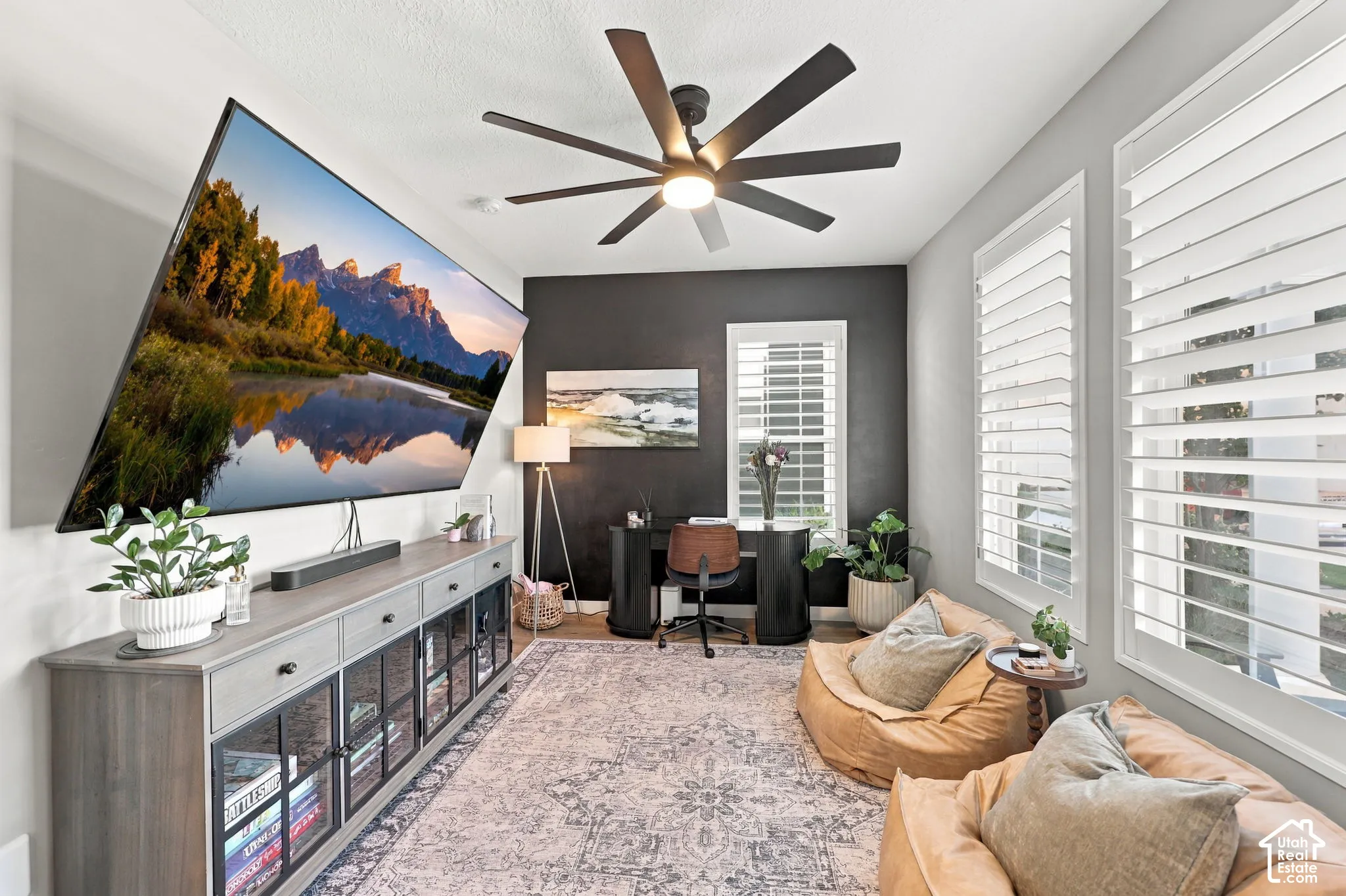 Built-in media console, ceiling fan with integrated lighting, window shutters, and a dark accent wall