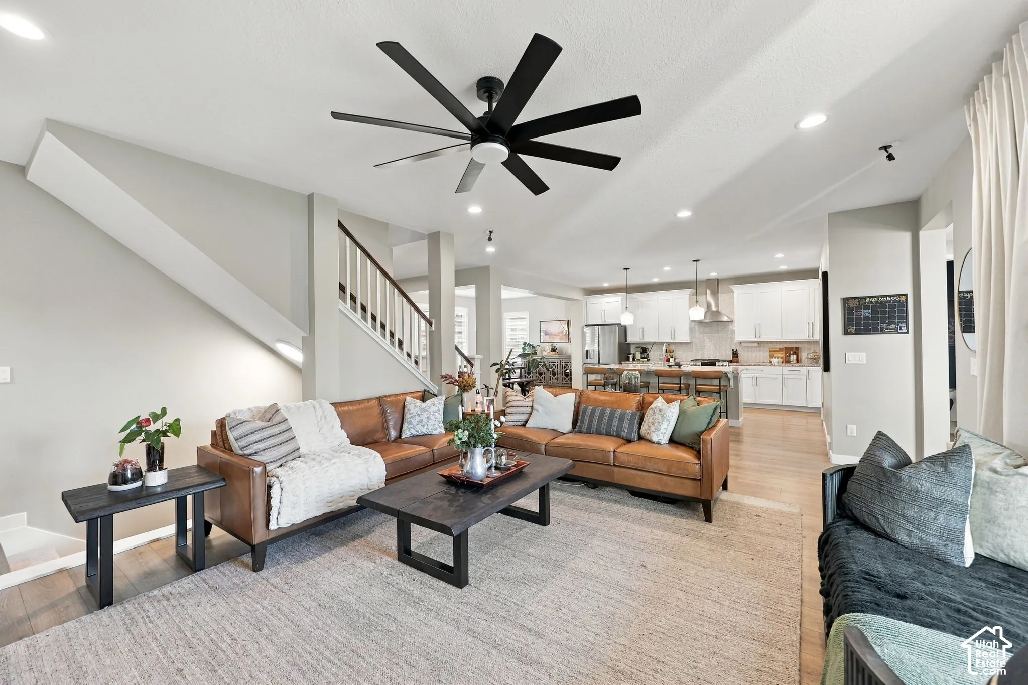 Open-concept living space with light-tone flooring, recessed lighting, and a contemporary ceiling fan