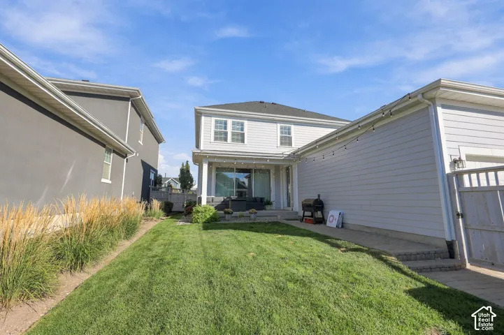 Expansive backyard featuring a manicured lawn, tiered paver patio, and low-maintenance landscaping