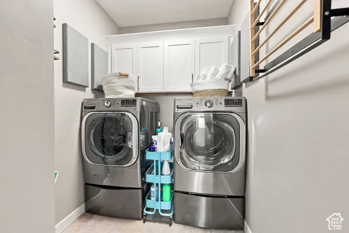 Laundry area featuring light wood-finish flooring, white shaker-style cabinetry, and a wall-mounted drying rack