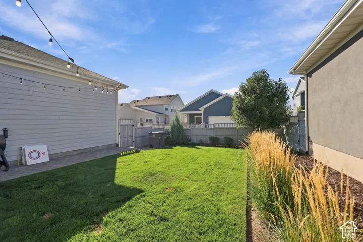 Expansive lawn area with a perimeter fence, mature landscaping, and an exterior string light installation