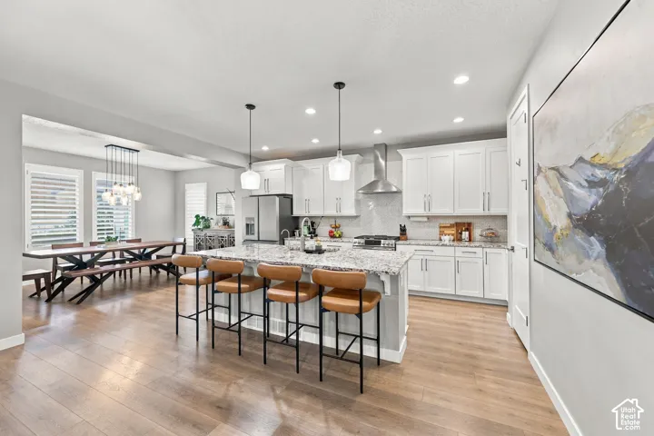 Open-concept kitchen and dining area featuring light wood-finish flooring, white cabinetry, a large kitchen island with counter seating, and recessed lighting