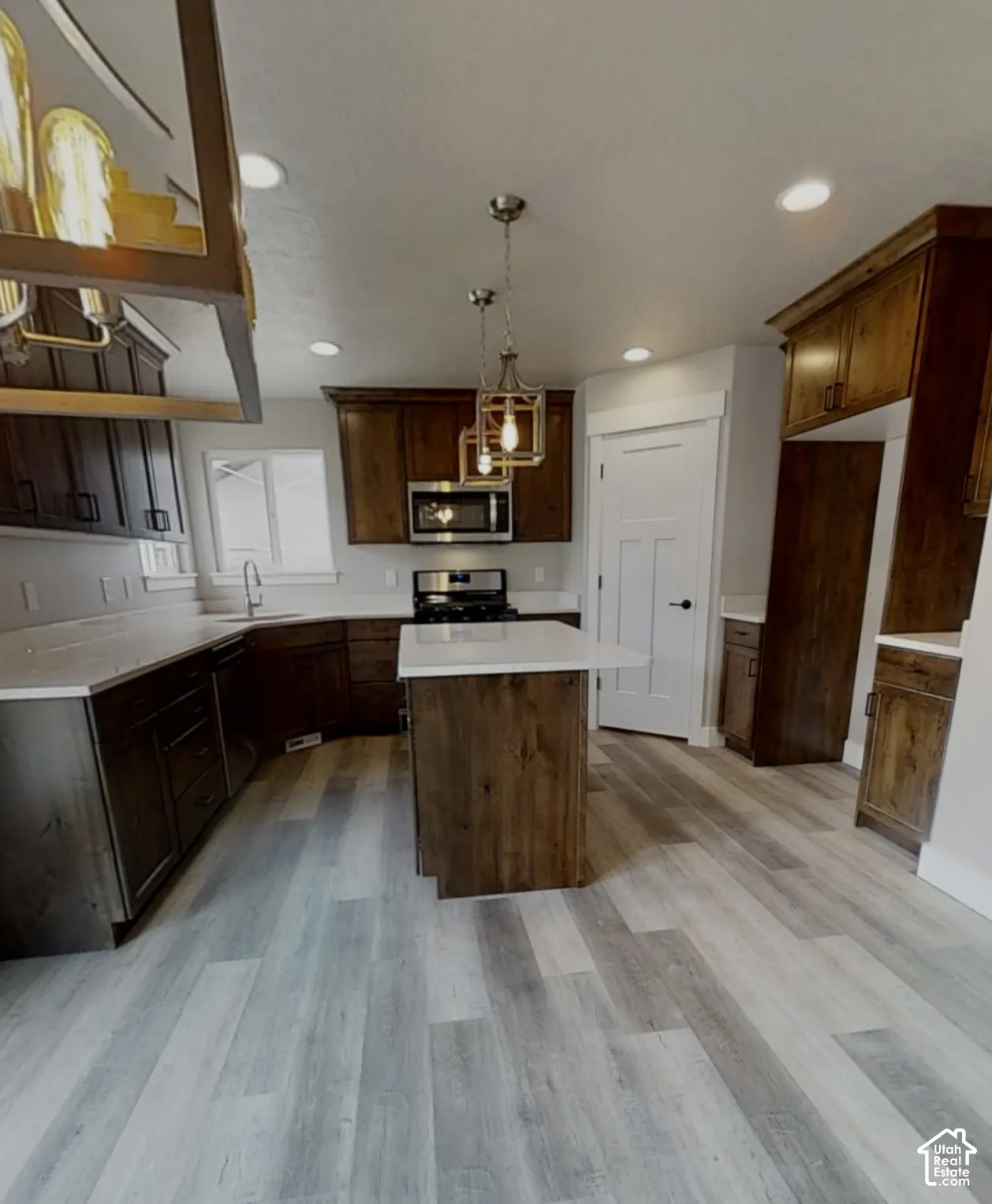 Kitchen featuring wood-finish flooring, dark wood cabinetry, white countertops, a central island, and recessed lighting