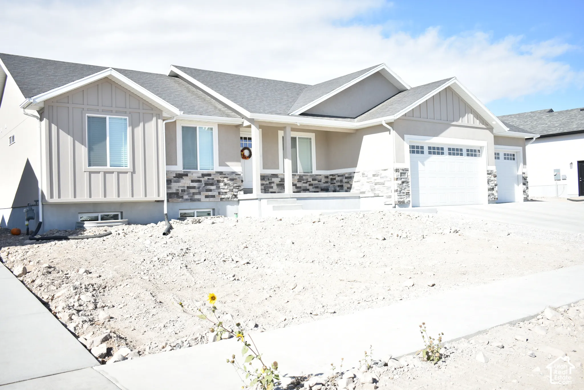 Contemporary exterior with stucco and board-and-batten siding accents, featuring a covered entry porch, a two-car garage, and a concrete driveway