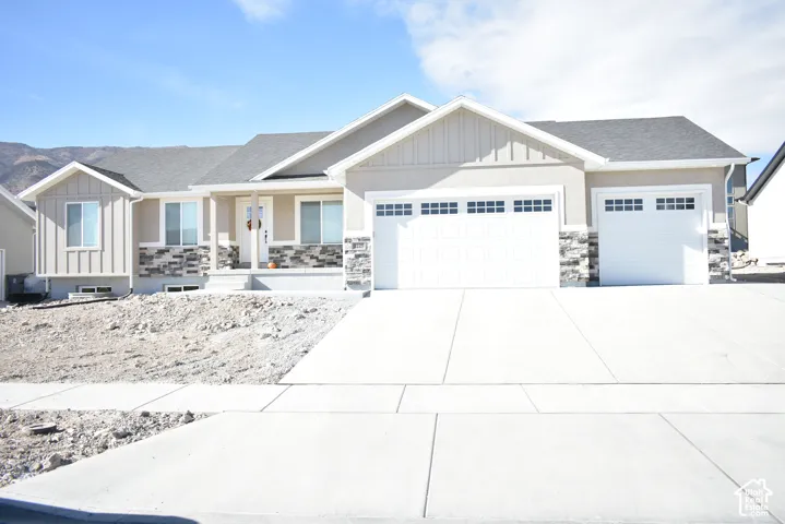 Exterior with a light-toned stucco and horizontal siding combination, stone facade accents, covered front porch, and an attached two-car garage