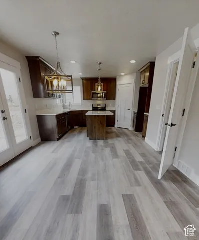 Kitchen featuring a central island, wood-finish flooring, dark wood cabinetry, and recessed lighting