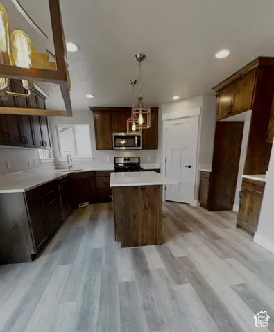 Kitchen featuring wood-finish flooring, dark wood cabinetry, white countertops, a central island, and recessed lighting