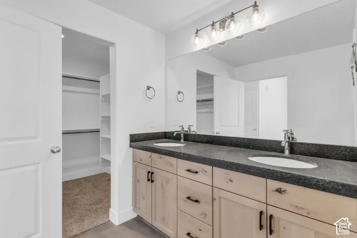 Primary bath with dual sinks, stained wood cabinets, quartz slab countertops and large walk-in shower.