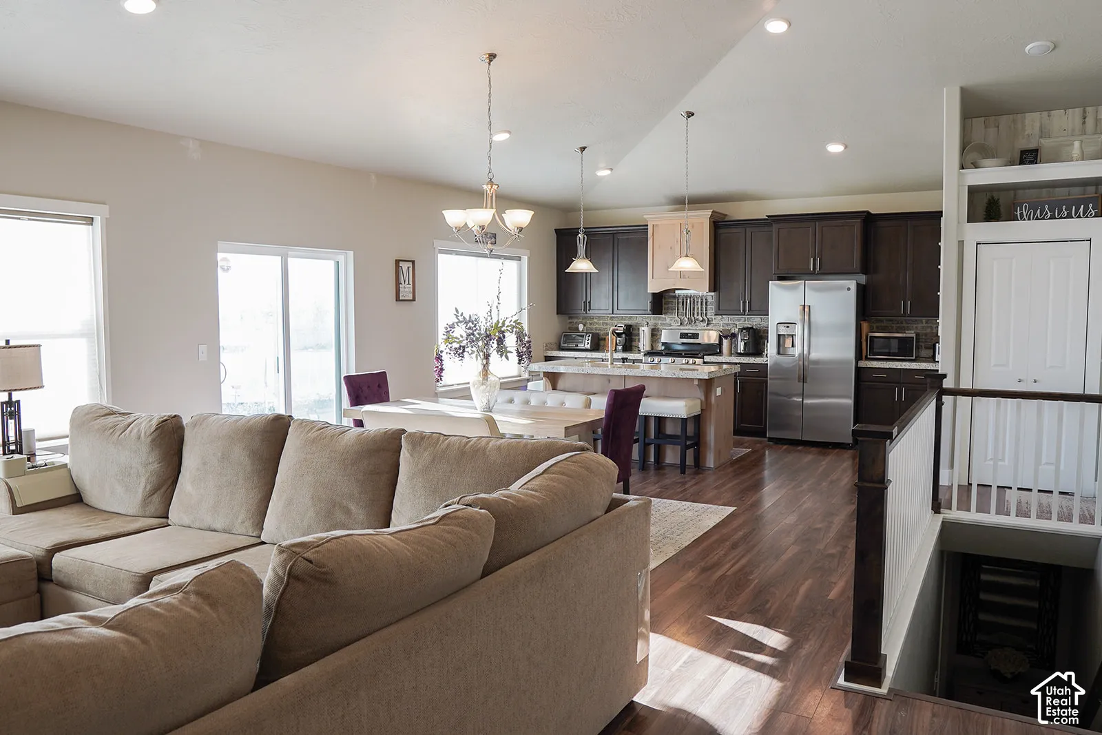 Open-concept living space featuring wood-finish flooring, recessed lighting, and a kitchen with stainless steel appliances