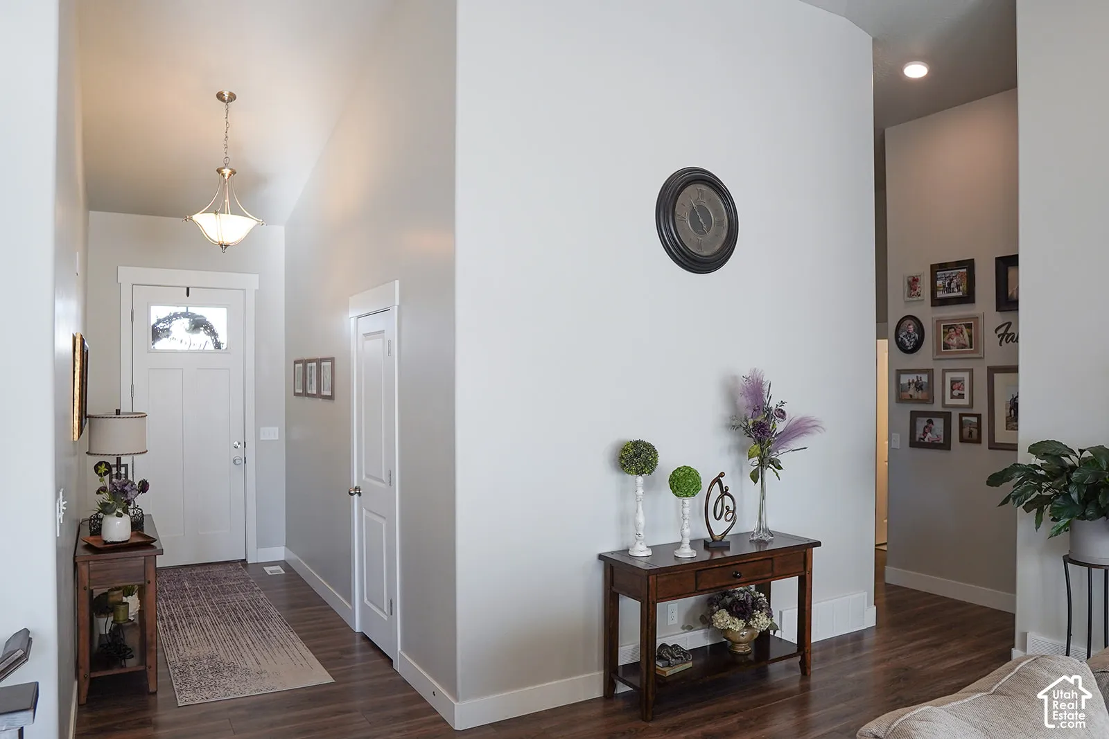 Wood-finish flooring throughout, bright white walls, recessed ceiling lighting, and a front entry door with an upper glass panel