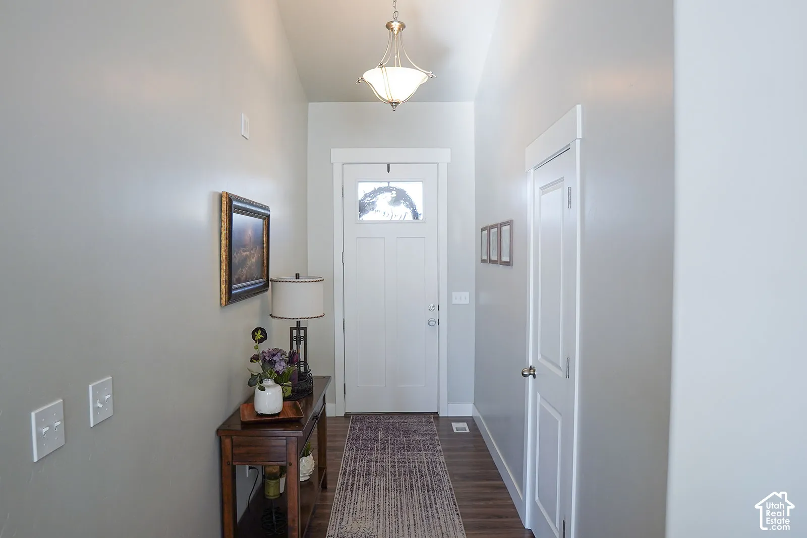 Wood-finish flooring leading to a white paneled entry door with decorative glass