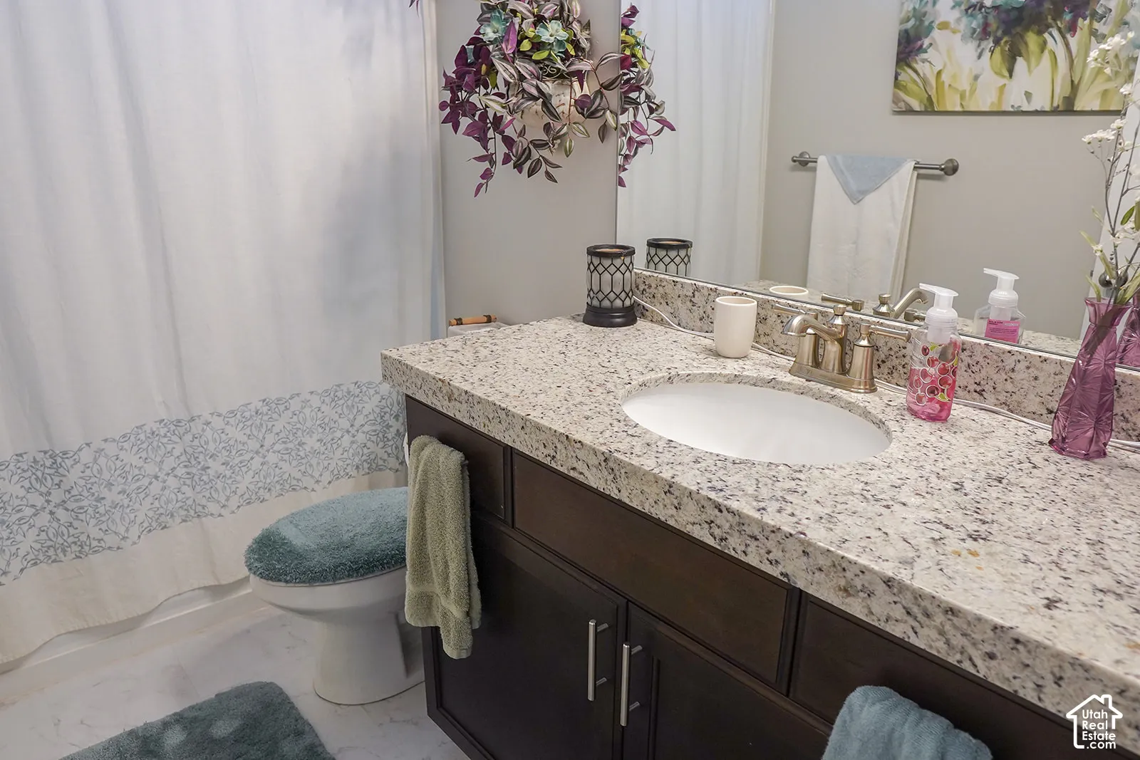 Vanity with a speckled countertop, undermount sink, and a dark wood-finish cabinet