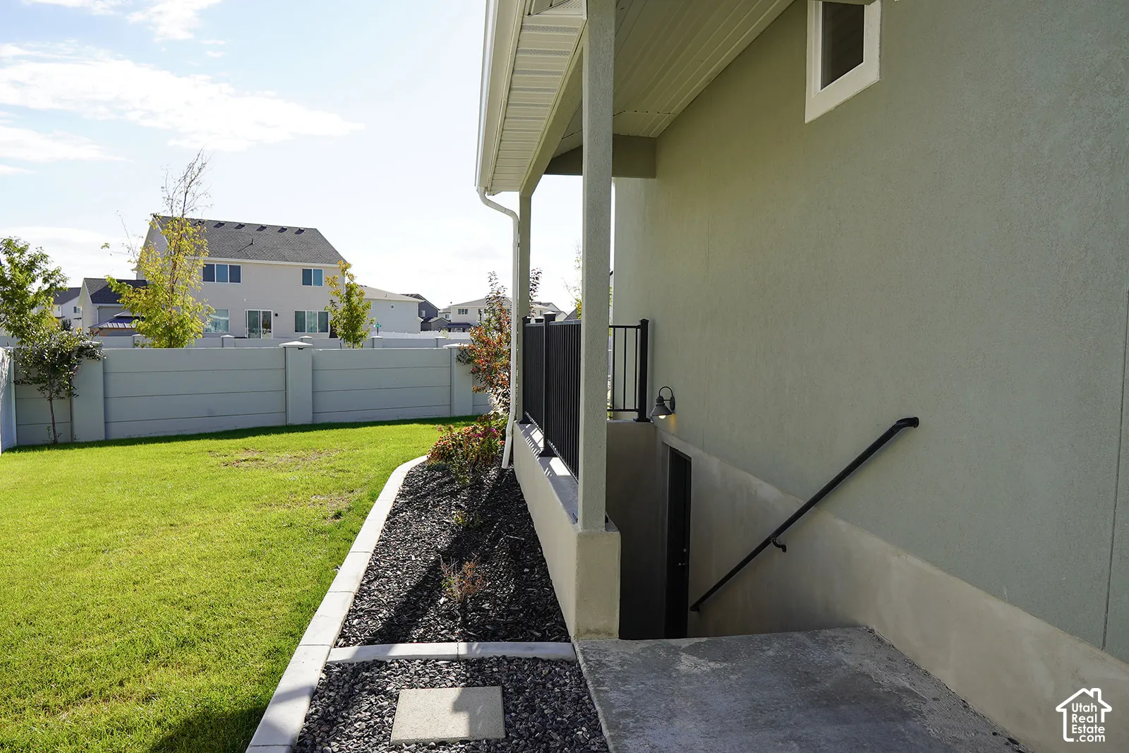 Finished basement entrance with a concrete staircase and black metal handrail