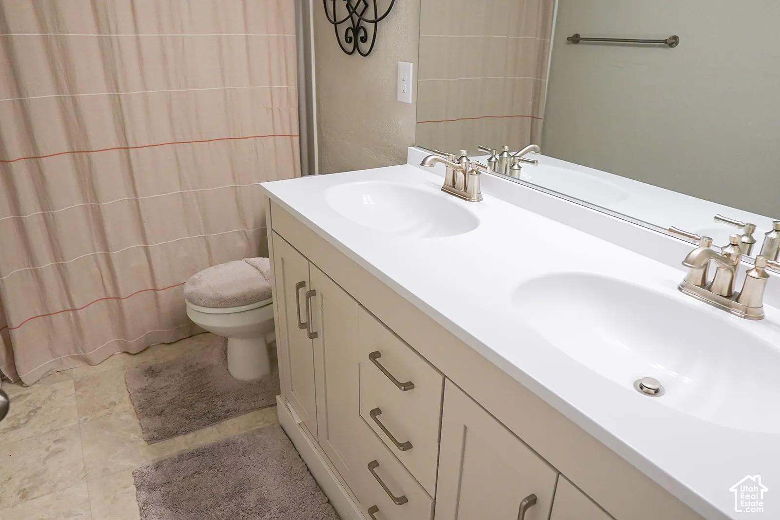 Double vanity with integrated sinks and brushed nickel faucets, set atop a light-toned cabinet with drawer and door storage