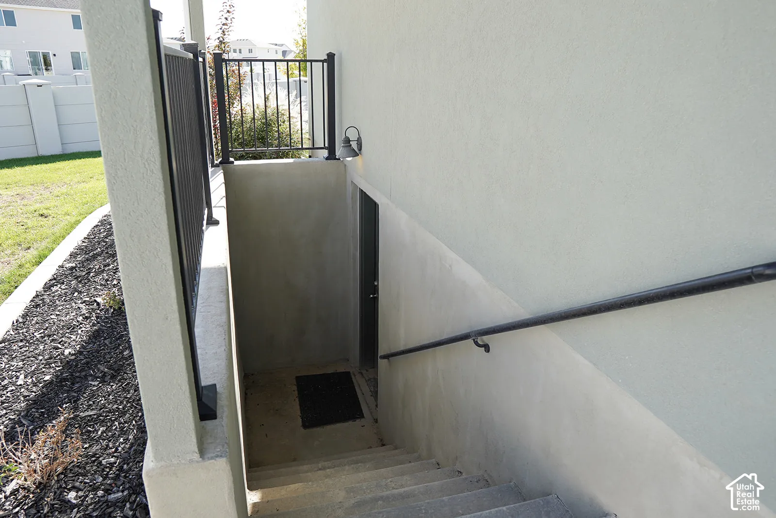 Concrete exterior stairs with a metal handrail, leading to an exterior door