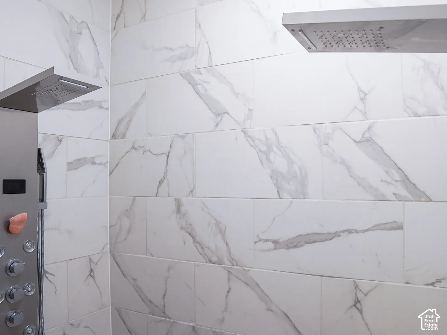 White marble-look wall tiling, dual rain shower heads, and an integrated shower panel