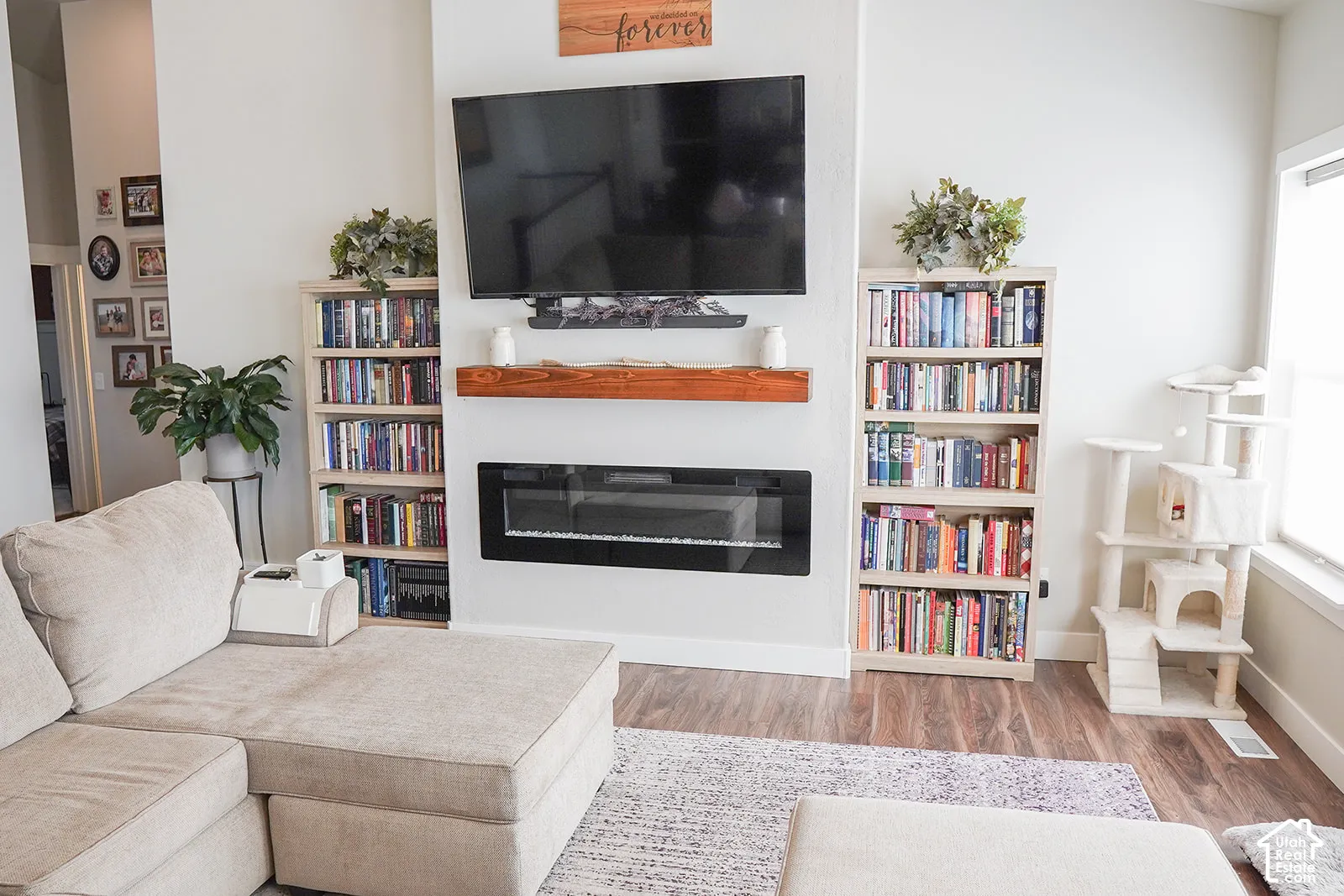 Built-in electric fireplace with a wood-finish mantel and two recessed shelving units, set against light-toned walls and wood-finish flooring