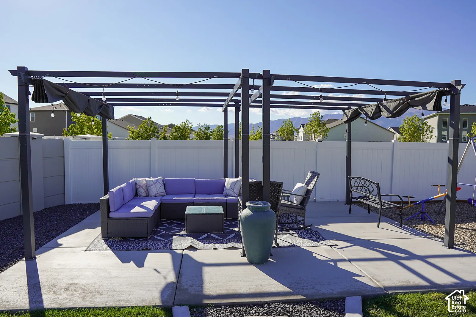 Spacious concrete patio featuring a large pergola with retractable shade covers and string lighting