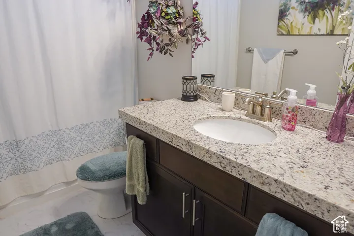 Vanity with a speckled countertop, undermount sink, and a dark wood-finish cabinet