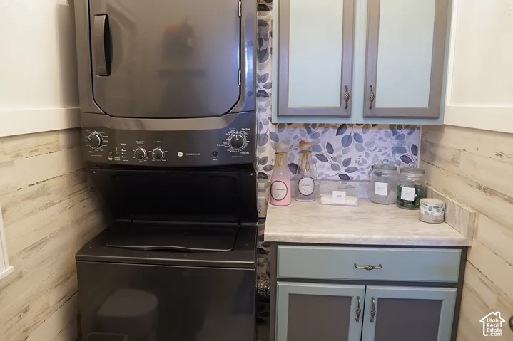 Stackable washer and dryer, patterned backsplash, wood-finish wall panels, and light-toned countertops