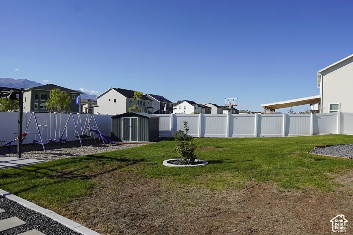 Expansive backyard featuring a manicured lawn, white privacy fencing, and a dedicated play area