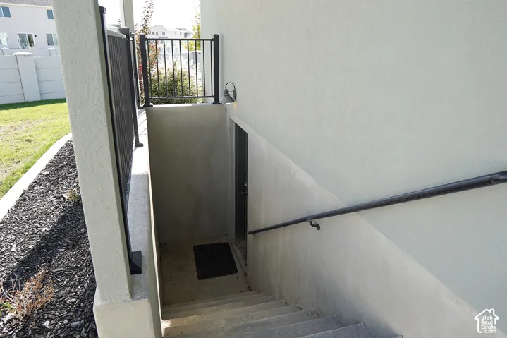 Concrete exterior stairs with a metal handrail, leading to an exterior door